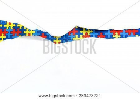 Torn White Paper On Multicolored Puzzle Background. Cocept For Autism Awareness Day. Break Barriers 