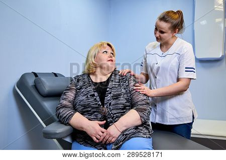 Young Inexperienced Female Doctor Taking Care Of A Fat Sick Woman On The Couch In The Medical Office