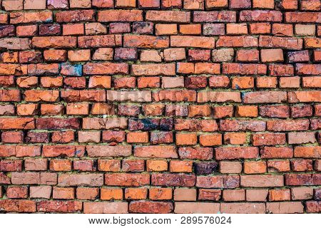Old Red Brick Wall With Cracks And Traces Of Paint