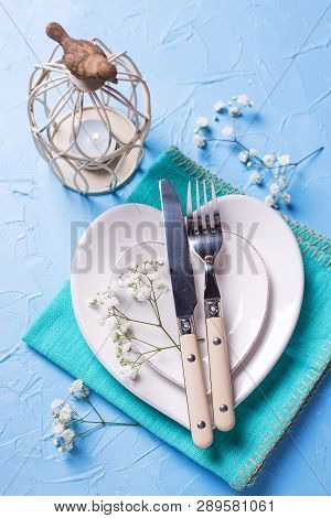 White Plates In Form Of Hearts, Napkin, Knife And Fork And  Fresh White Gypsofila  Flowers On Blue T