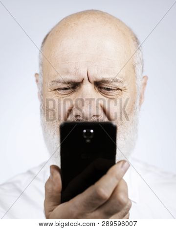 Senior Man Using A Phone And Having Eyesight Problems