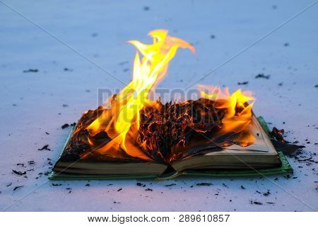 Burning Book In  Snow. Pages With The Text In  Open Book Burn With  Bright Flame.