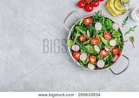 Fresh Salad With Green Leaves Of Arugula, , Spinach, Beets, Radish And Tomato On A Gray Stone Backgr
