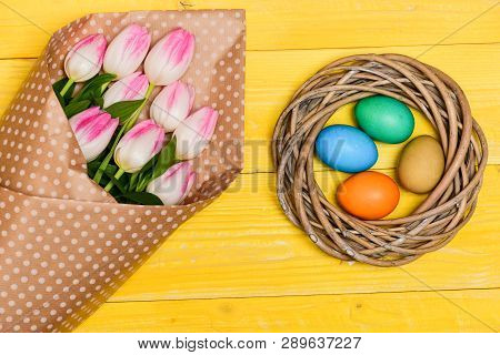 Colorful Eggs And Bouquet Fresh Tulip Flowers On Yellow Background Top View. Spring Holiday. Traditi