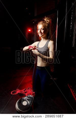 Young Sportswoman Pulls Bandages Around Her Arms While Standing In Ring During Training.