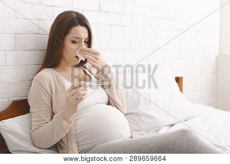 Pregnancy Illness. Young Pregnant Woman Feeling Sick With High Fever, Lying On Bed And Measuring Tem
