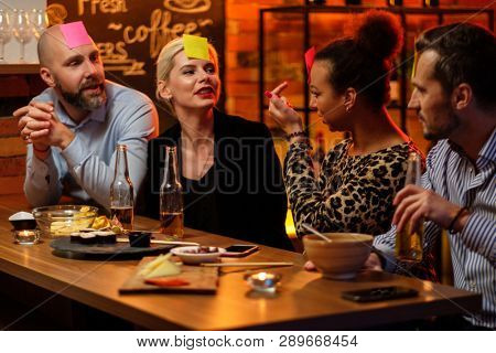 Group of friends playing sticky head game behind bar counter in a cafe