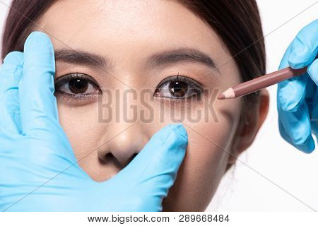Surgery Concept. The Doctor Is Drawing A Pencil On The Patient's Face. The Patient Is Confident In T
