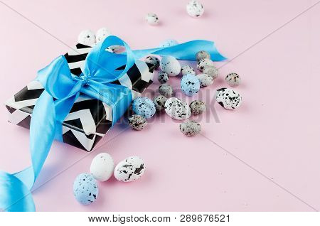 Gift With Blue Ribbon Small Easter Candy Eggs And Willow Twigs On Light Pink Background, Top View, C