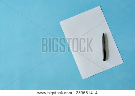 White Sheet Paper With Black Pen On Blue Background With Copy Space For Text. Print Disign Consept.