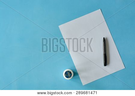White Sheet Paper With Black Pen And Colored Different Pills, Capsules On Blue Background With Copy 