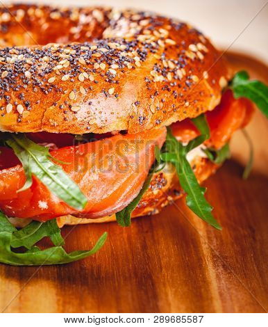 Bagel With Cream Cheese, Smoked Salmon And Arugula Salad On Wooden Board. Close Up