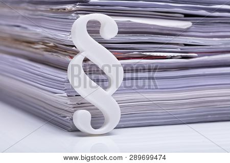 Close-up Of Red Paragraph Symbol Leaning On Documents