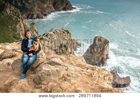 Woman, Girl With A Dog Sitting On The Shore Of The Atlantic Ocean