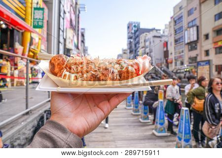 Osaka, Japan - 4 Mar 2018: Takoyaki, The Local Japanese Octopus Meat Ball In The Hand Beside The Can