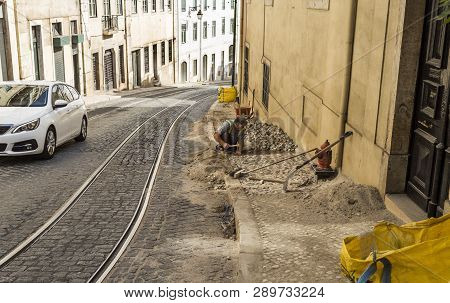 Lisbon - July 3, 2018: View Of A Traditional Professional Paviour Person Laying Cobblestones On A Si