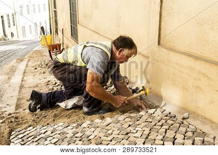 Lisbon - July 3, 2018: View Of A Traditional Professional Paviour Person Laying Cobblestones On A Si