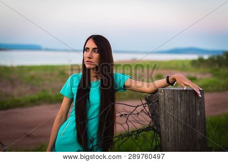 Portrait Of Young Beautiful Girl In A Turquoise Dress Near Barbed Wire In Summer Outdoor