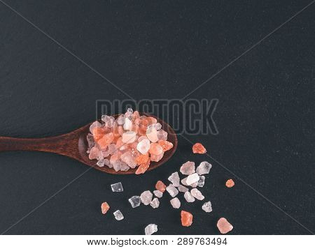 Himalayan Pink Salt In Spoon On Black Stone Background. Copy Space
