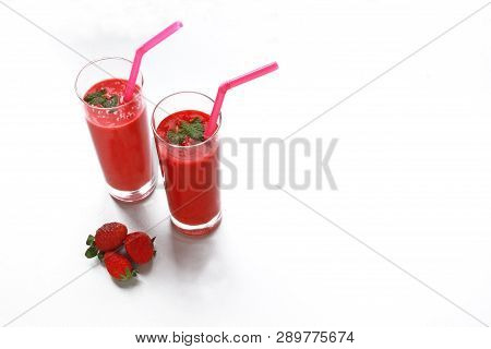 Two Strawberry Smoothies And Some Strawberries On White Background