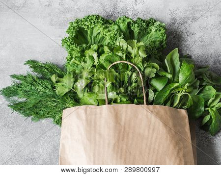 Healthy Green Vegan Ingredients For Cooking. Various Herbs And Keil In Paper Bag On Grey Background.