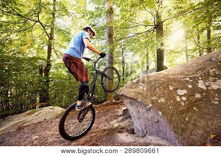 Young Portsman Cyclist Riding On Back Wheel On Trial Bike, Man Rider Balancing On The Edge Of Big Bo
