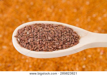 Flaxseed Grains In Spoon On Orange Background.