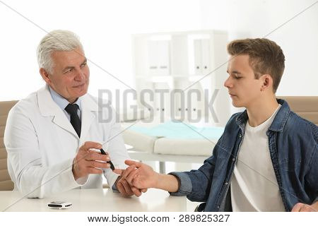 Doctor Taking Patient's Blood Sample With Lancet Pen In Hospital. Diabetes Control