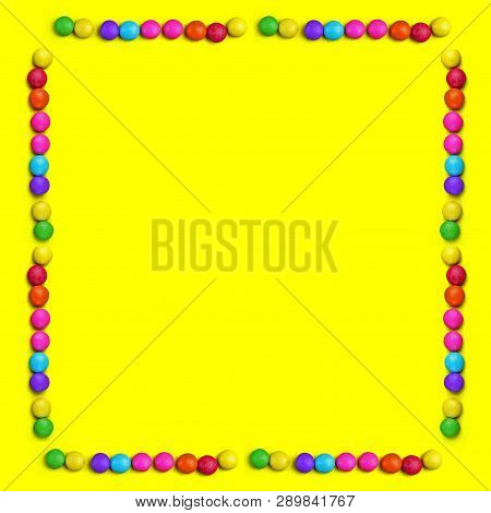 Yellow Background With Frame Of Colorful Chocolade Smarties . It Is Can Be Banner Or Universal Happy