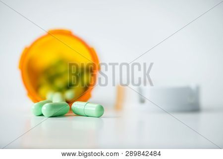 Prescription Medicine Green Capsules Cascading Out Of Orange Pharmacy Bottle