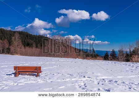 A park bench with gorgeous view at mountains and blule sky with white clouds, British Columbia, Canada.
