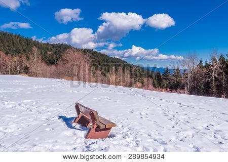 A park bench with gorgeous view at mountains and blule sky with white clouds, British Columbia, Canada.