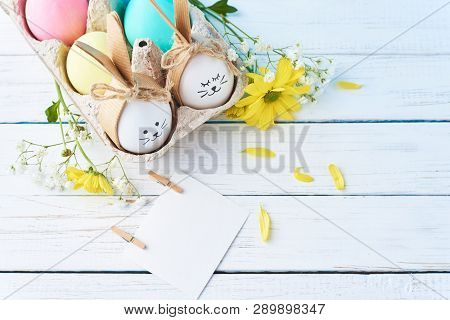 Easter Colored Eggs With Painted Faces In Paper Tray With Decorationd On White Background