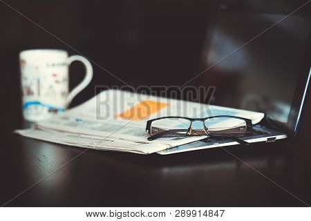 Laptop, Newspaper And Glasses On The Table.