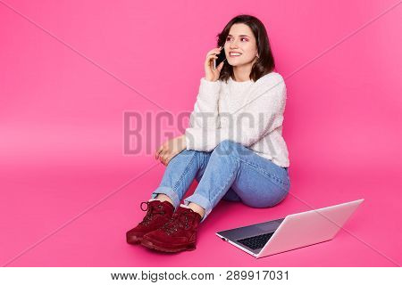 Attractive Female With Beautiful Smile Sits On Floor At Home, Speaks On Mobile Phone. Beautiful Girl