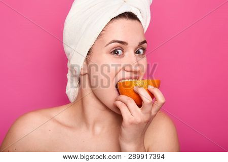 Portrait Of Attractive Woman With Nacked Shoulders, Girl Eats Orange And Looks At Camera. Charming F