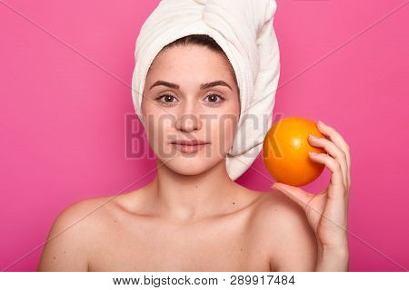 Beauty Portrait Of Young Girl With Nacked Shoulders. Lady Holds Orange, Has Calm Facial Expression. 