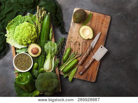 Assorted Green Toned Raw Organic Vegetables In Wooden Box On Dark Stone Background. Avocado, Cabbage