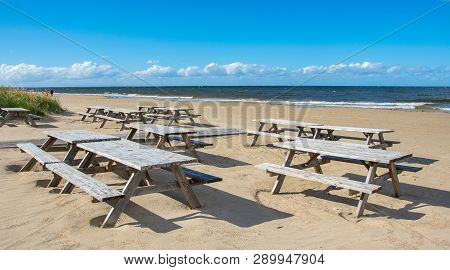 Wooden Tables And Benches Of A Summer Cafe On A Deserted Beach In The Bright Sunny Day Of The Beginn