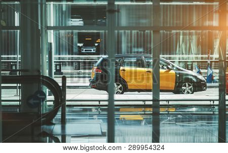A Modern Yellow Taxi Car Passing By, View Through The Window Of A Contemporary Airport Terminal Or A