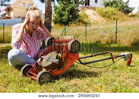 Gardening. Female Person Gardener Mowing Green Lawn With Lawnmower, Having Problem With Broken Mower