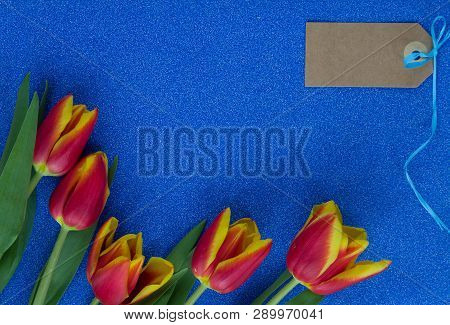 Red And Yellow Tulips On Blue Glitter Background With Copy Space