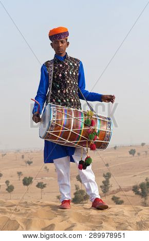 Indian Drummer In Traditional Clothes Playing In Desert