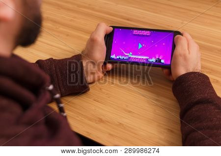 Prague, Czech Republic - March 16, 2019: Man Holding A Smartphone And Playng The Geometry Dash Mobil