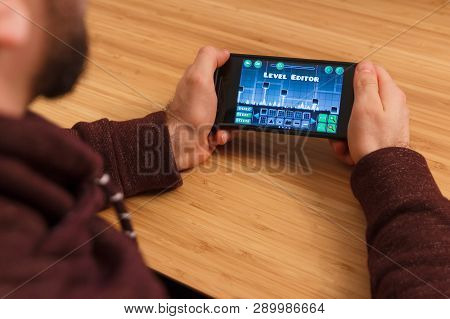 Prague, Czech Republic - March 16, 2019: Man Holding A Smartphone And Playng The Geometry Dash Mobil