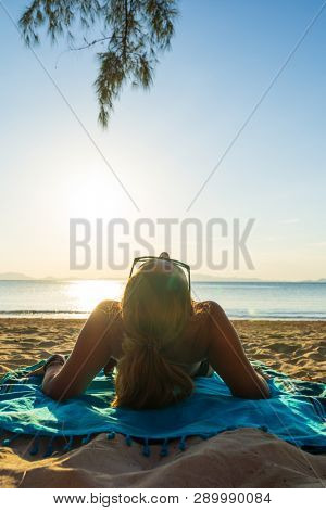 Woman enjoying her holidays on a transat at the tropical beach in Thailand - intentionnal lens flare