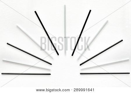 A Group Of Black Grey Plastic Straws On White Paper Background