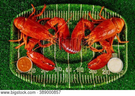 Two Red Cooced Lobsters On Green Plate With Football Ball. American Football Concept.