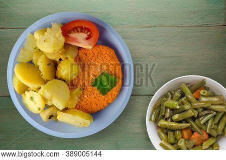 Meatball With Potatoes On Green Wooden Background. Meatball With A Slice Of Tomato On Light Blue Pla