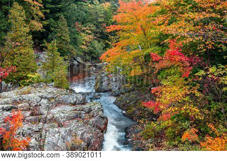 Running water of Dead river through rocky terrain in Michigan Upper Peninsula with colorful fall foliage
